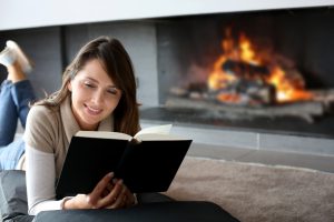 woman reading infront of fireplace